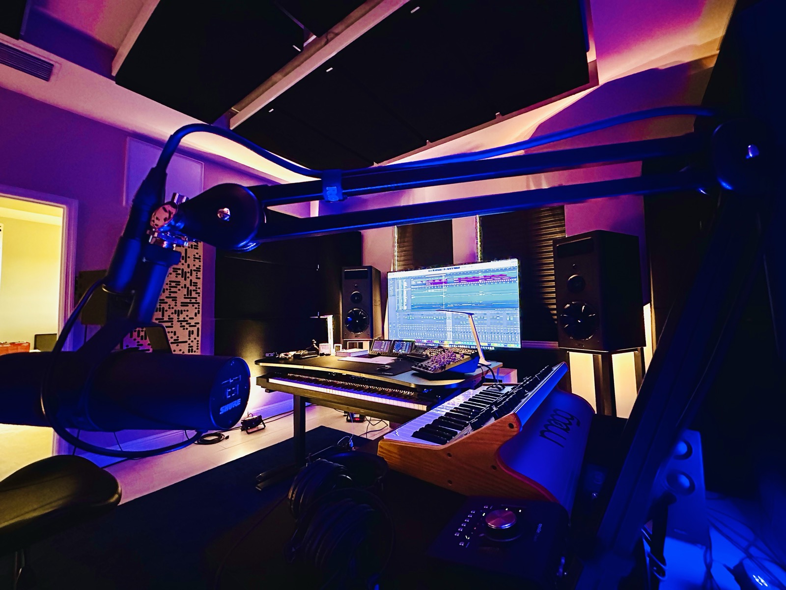 Studio with foreground microphone, keyboards, monitor speakers and acoustic treatment